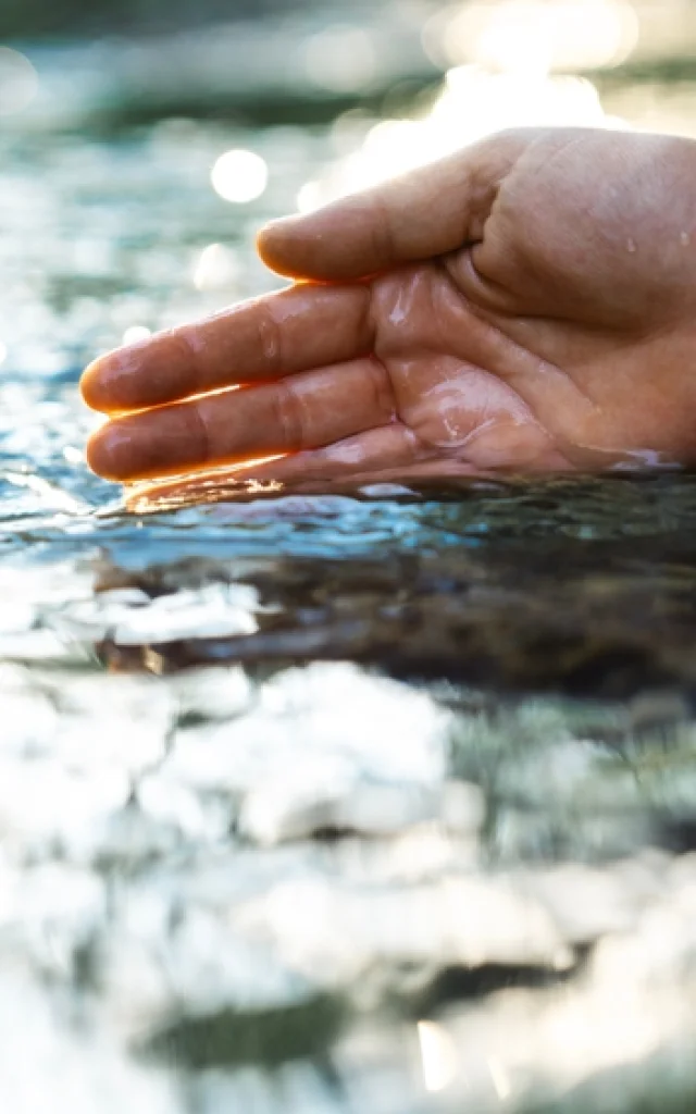 Main plongeant dans l'eau d'une rivière
