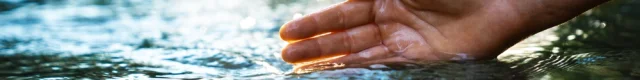 Main plongeant dans l'eau d'une rivière