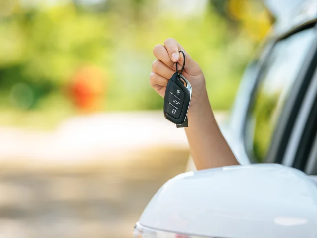 girl sitting in the car and holding the car keys hands out of the car.