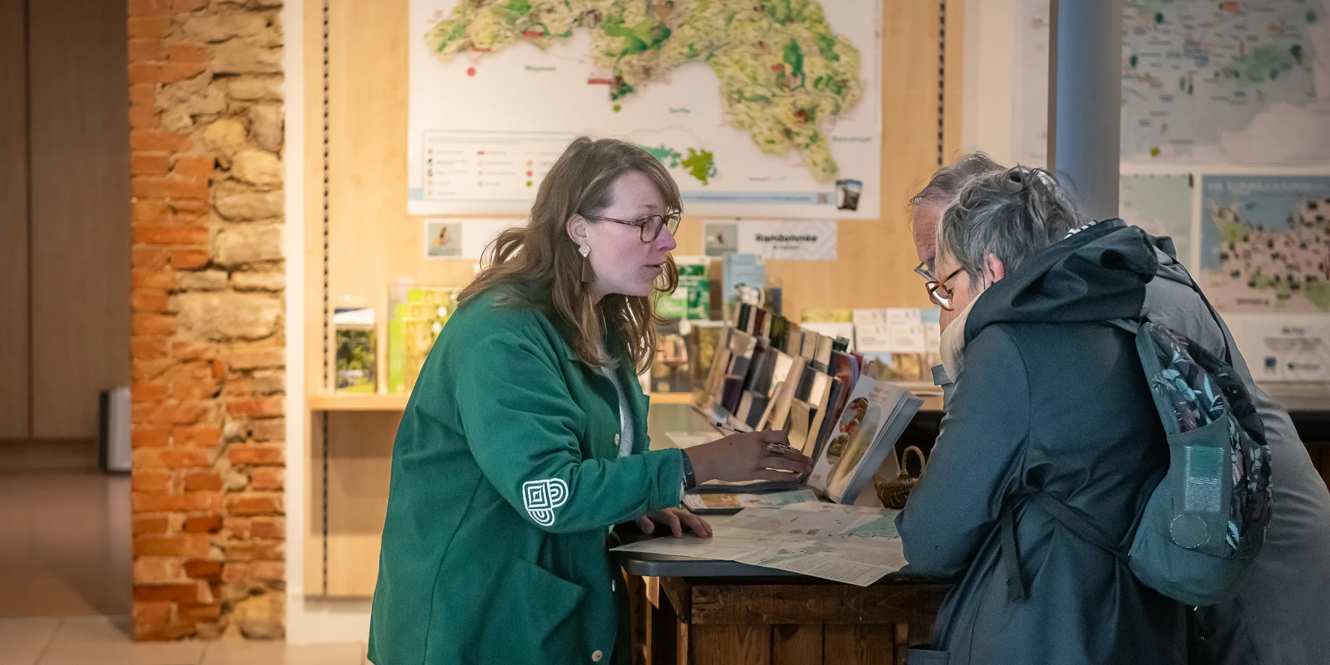 Conseillère en séjour renseignant des visiteurs à l'accueil d'Alençon Tourisme