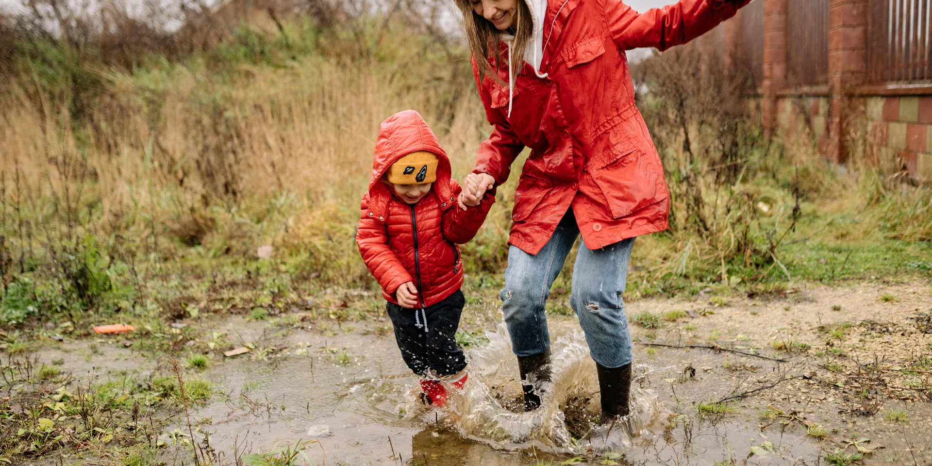 Une maman et son enfant sautant dans une flaque d'eau