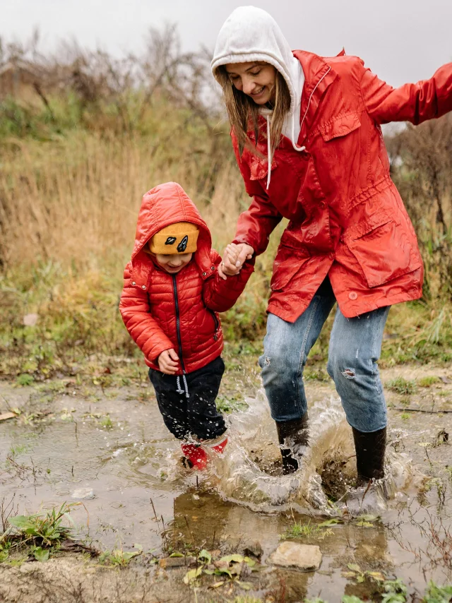 Une maman et son enfant sautant dans une flaque d'eau