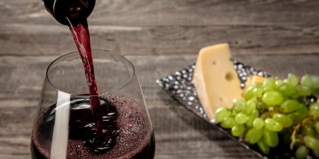 Bottle And Glass Of Red Wine With Fruits Over Wooden Table Min