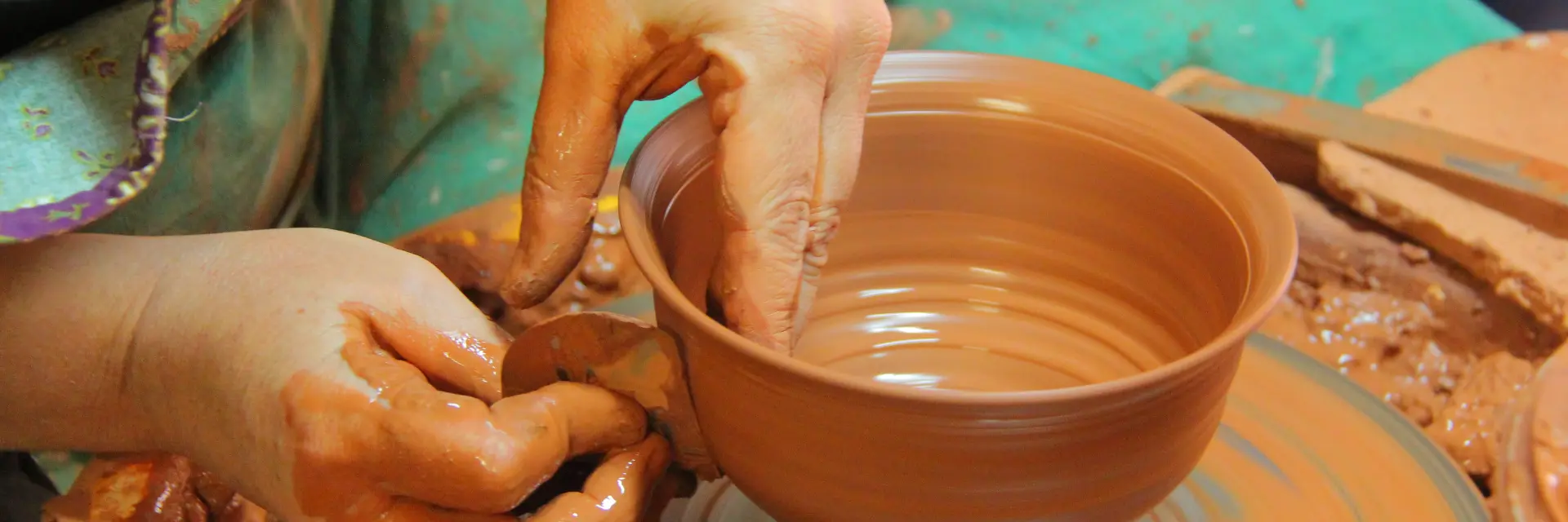 Mains d’un potier façonnant un bol en argile sur un tour de poterie à l'atelier Hostein Noe à Aubagne