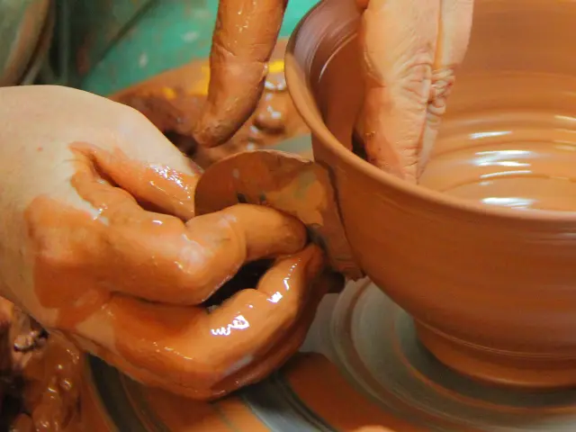 Mains d’un potier façonnant un bol en argile sur un tour de poterie à l'atelier Hostein Noe à Aubagne