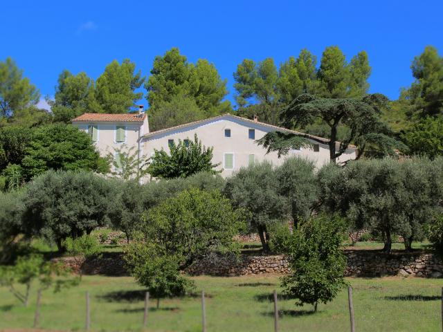 Bastide provençale entourée d’oliviers, de pins et de verdure dans un paysage rural méditerranéen sous un ciel bleu dégagé au domaine de Font de Mai à Aubagne