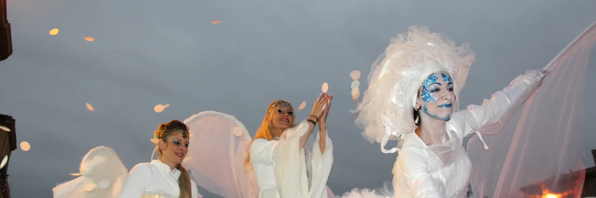 Artistes vêtus de costumes blancs et lumineux participant à une parade de Noël en soirée à Aubagne