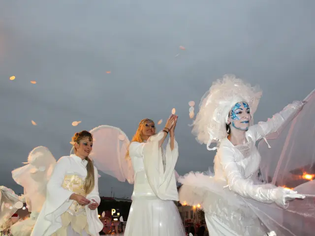 Artistes vêtus de costumes blancs et lumineux participant à une parade de Noël en soirée à Aubagne