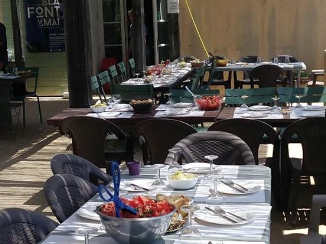 Tables dressées sous une pergola en bois pour un repas en plein air dans un environnement naturel à la buvette du domaine de font de mai à Aubagne