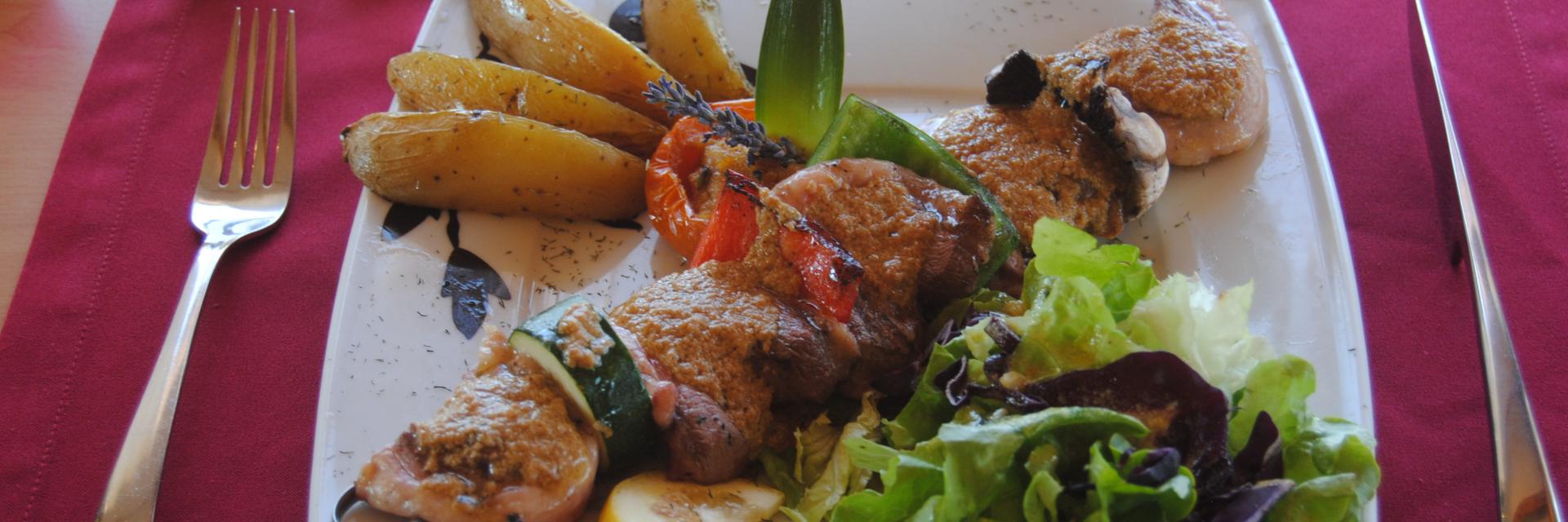 Assiette de viande grillée accompagnée de pommes de terre rôties, légumes grillés et salade verte, servie sur une table de restaurant à Aubagne