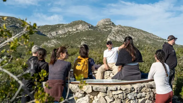 Groupe de visiteurs à la table d'orientation de la font de mai, avec le garlaban en fond