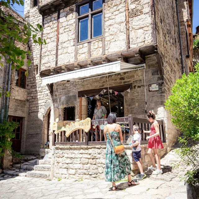 Une famille discute avec une commerçante de Sainte-Enimie