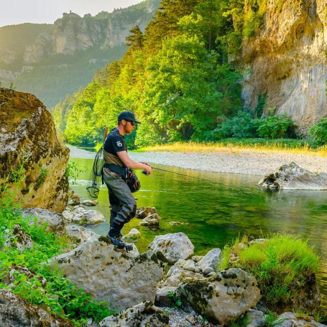 A fisherman on a bank of the Tarn surrounded by cliffs
