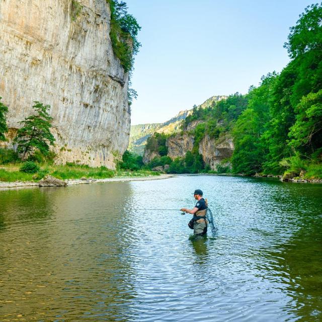 A fisherman in the Gorges du Tarn weighing faec on the cliffs