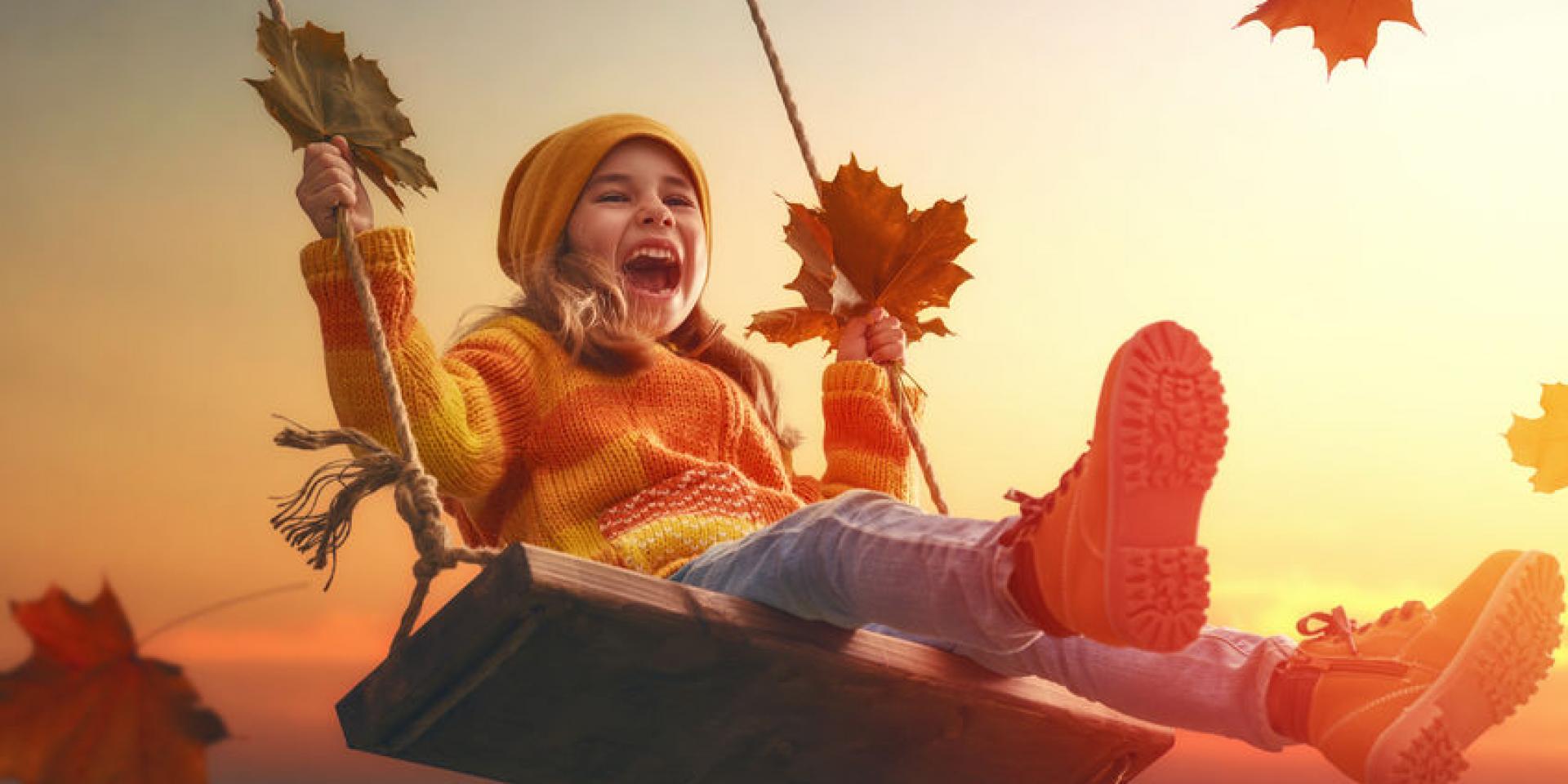 Happy child girl on swing in sunset fall. Little kid playing in the autumn on the nature walk.