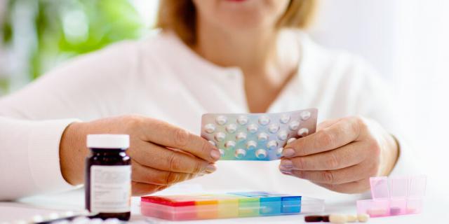 Pill box for senior patient. Medicine container. Elderly woman sorting drug pills for pain relief and disease treatment. Sick retired female with drugs. Daily vitamins for healthy retirement.