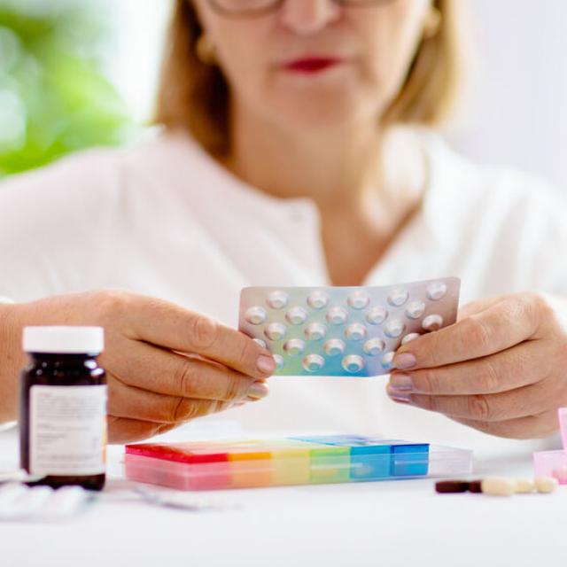 Pill box for senior patient. Medicine container. Elderly woman sorting drug pills for pain relief and disease treatment. Sick retired female with drugs. Daily vitamins for healthy retirement.