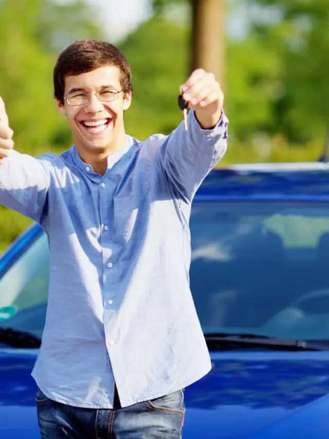 Young happy man in glasses standing in front of his new car and showing thumb up and car key