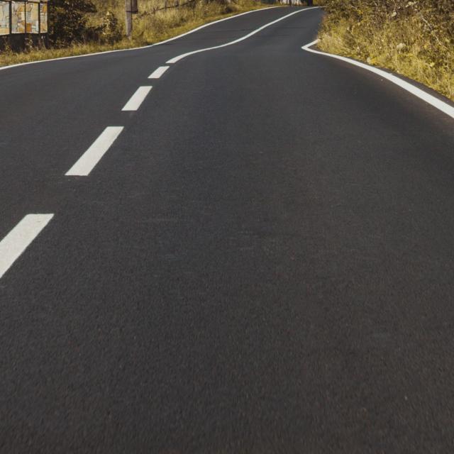 A vertical shot of an empty asphalt road through mountains under a cloudy sky