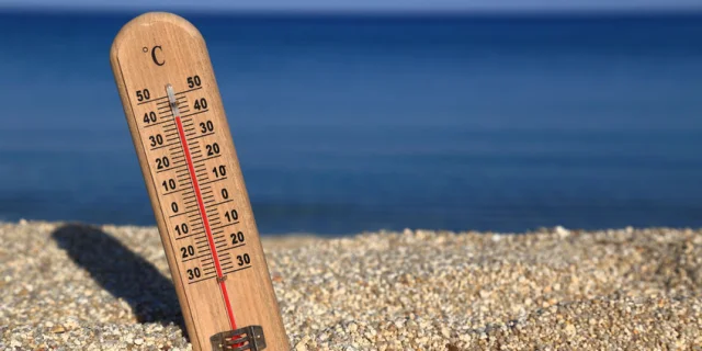 Thermometer on a beach shows high temperatures