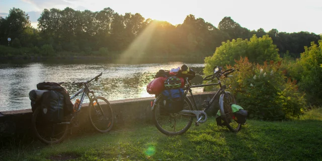 deux vélos dont un avec des sacs garés le long de l'eau