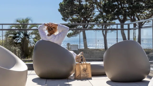 Eine Frau, die sich mit Blick auf das Meer im Teeraum des Thalasso-Relais sonnt.