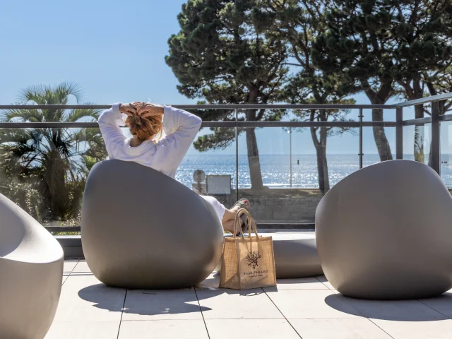 Une femme se prélassant face à la mer dans l'espace Tisanerie du Relais Thalasso