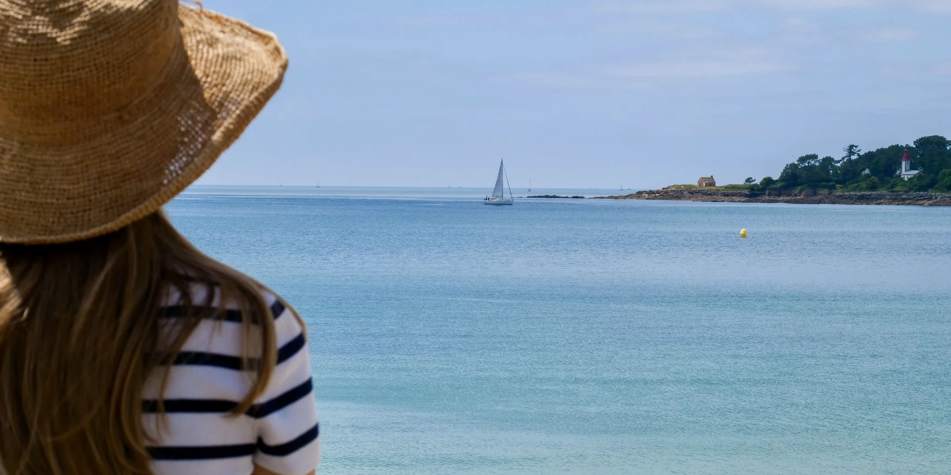 Junge Frau bewundert die Pointe de Combrit vom Plage du Trez in Bénodet aus