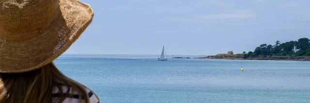 Junge Frau bewundert die Pointe de Combrit vom Plage du Trez in Bénodet aus