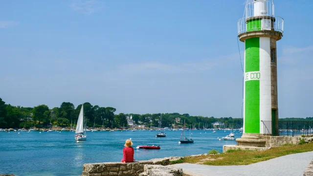 Junge Frau sitzt in der Nähe des Leuchtturms Phare du Coq in Bénodet