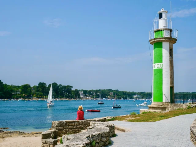 Junge Frau sitzt in der Nähe des Leuchtturms Phare du Coq in Bénodet