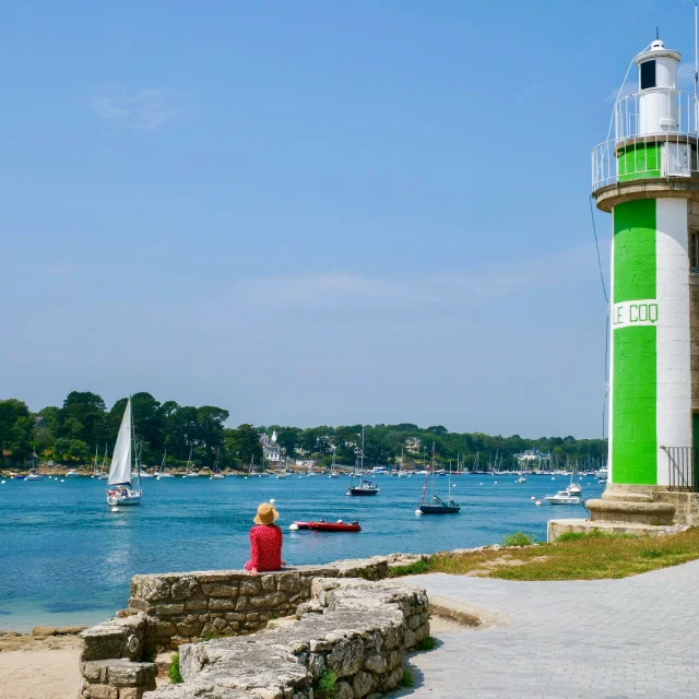 Junge Frau sitzt in der Nähe des Leuchtturms Phare du Coq in Bénodet