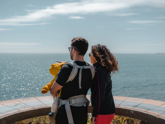 Jeunes parents et leur bébé admirant l'horizon depuis la table d'orientation de la Pointe de Groasguen