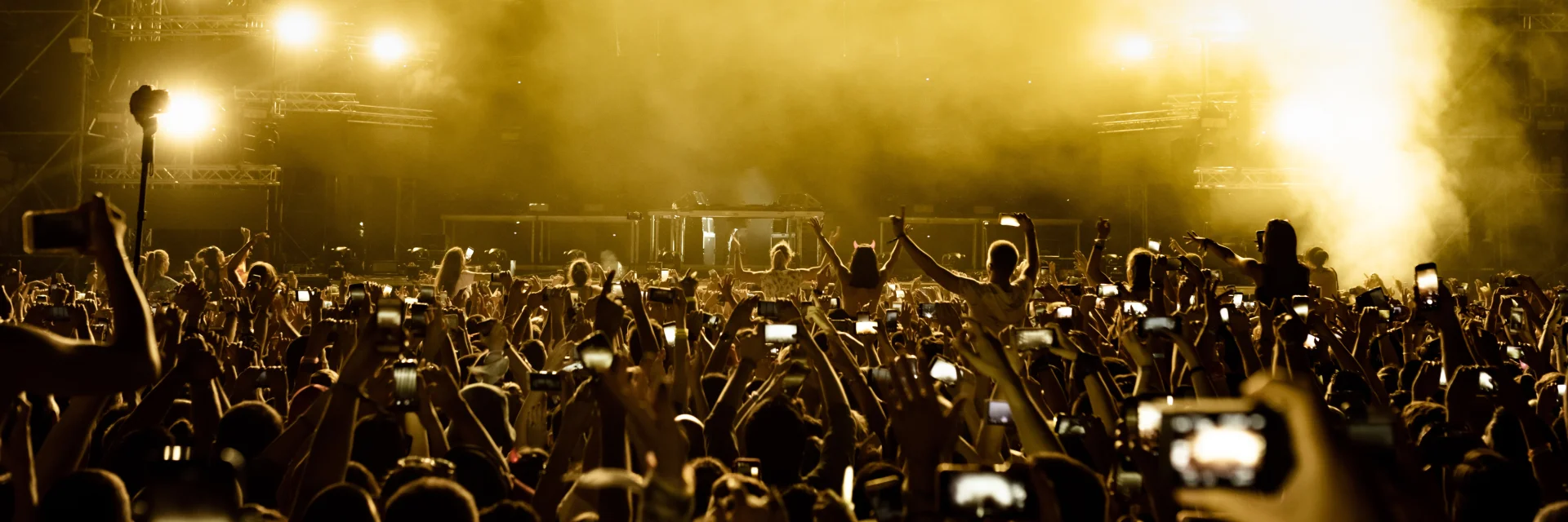 Vorderansicht von aufgeregten Fans, die Spaß auf dem Musikfestival haben und mit ihren Smartphones Bilder von der Bühne machen.  Kopierraum.