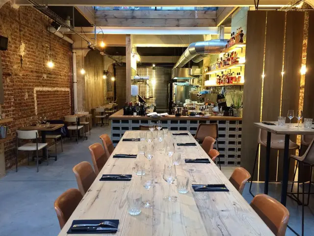 Salle du restaurant Holy Smoke à Bruxelles avec grande table en bois