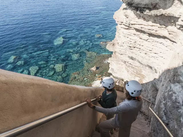 Visiteurs équipés admirant la vue depuis l'Escalier du Roy d'Aragon à Bonifacio