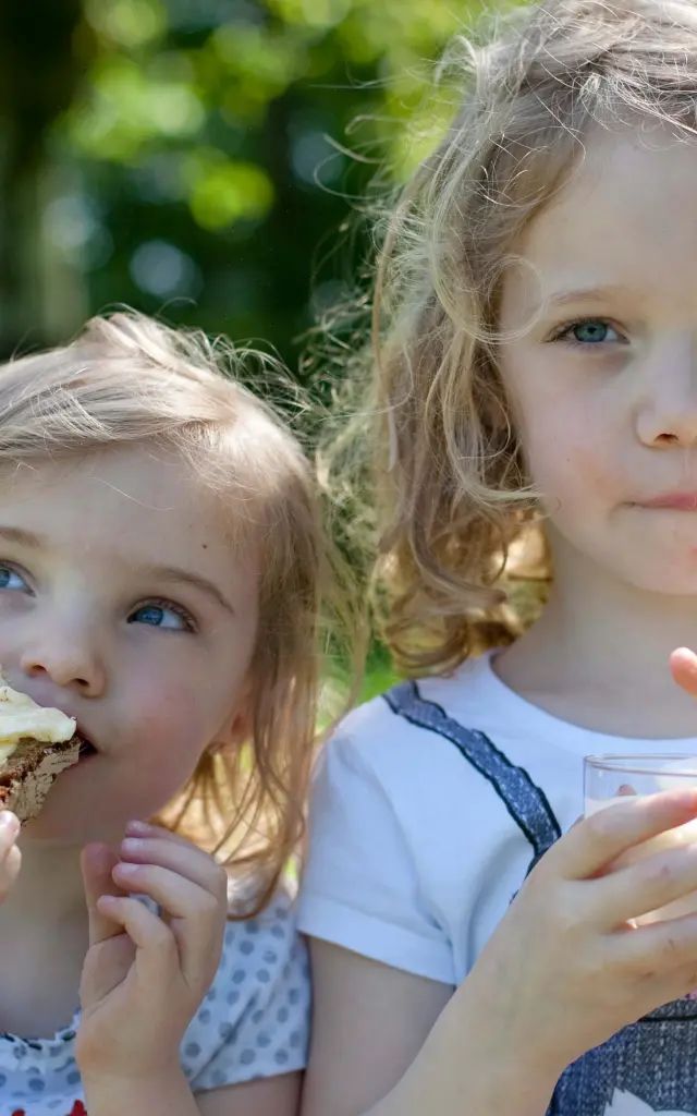 Deux petites filles qui grignotent une tartine de pain avec du beurre de Bresse AOP