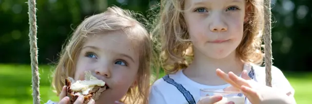 Deux petites filles qui grignotent une tartine de pain avec du beurre de Bresse AOP