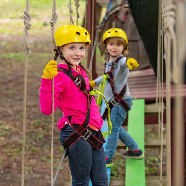 Artworks depict games at eco resort which includes flying fox or spider net. Portrait of a beautiful kid on a rope park among trees. Cargo net climbing and hanging log