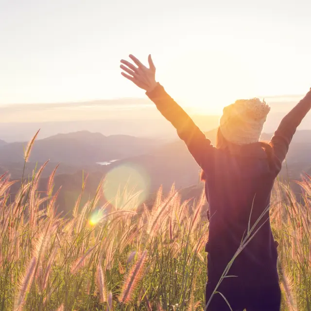 Une femme épanouie devant le joli lever du soleil.