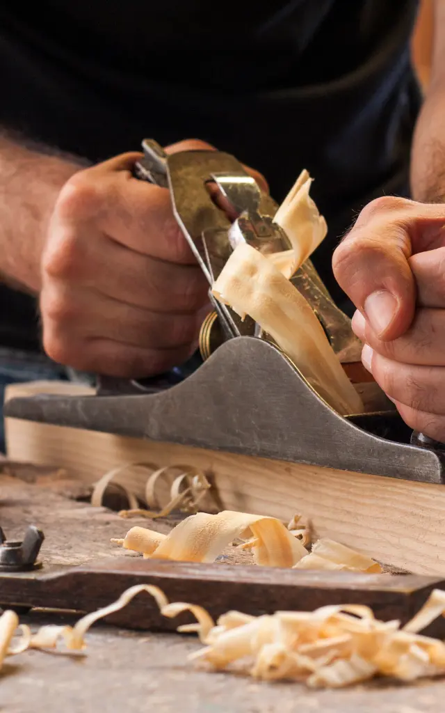 carpenter working with plane on wooden background
