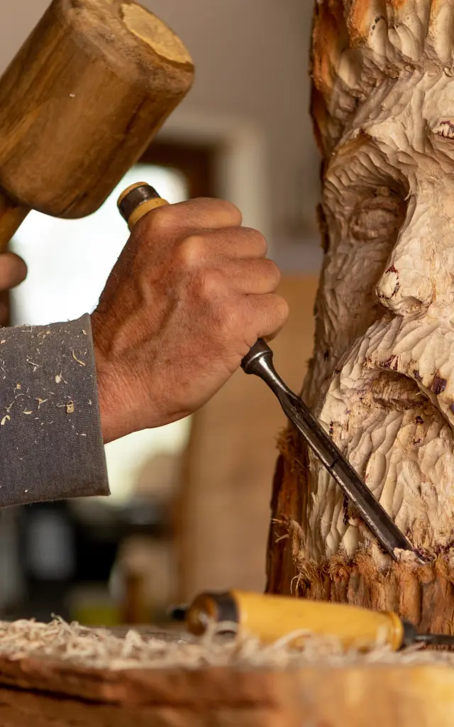 close up of hand carving wood spirit sculpture by skillful artisan wood worker