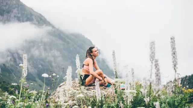 Sportieve vrouw ontspant op bergklif boven de wolken. Alleen reizen gezonde levensstijl. Gezond leven Concept.