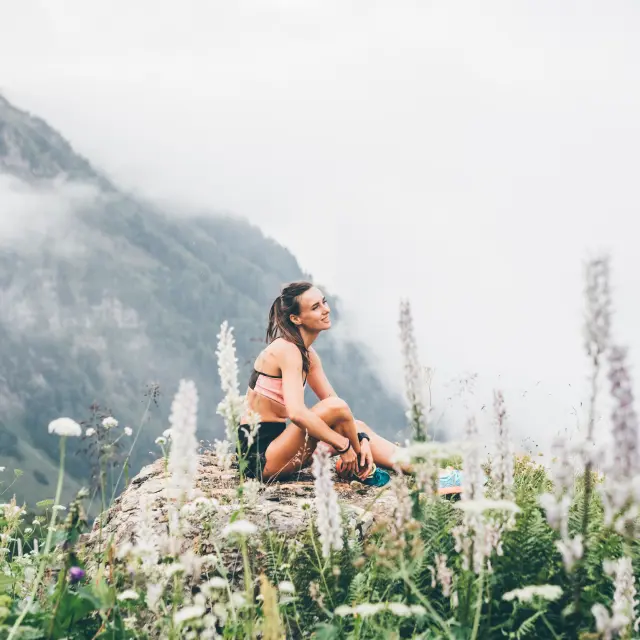 Sport woman relaxing on mountain cliff above the clouds. Alone travel healthy lifestyle. Healthy life Concept.
