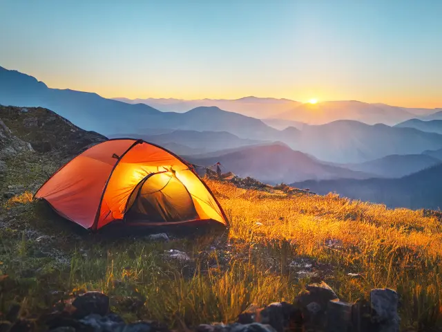 tourist tent camping in mountains at sunset