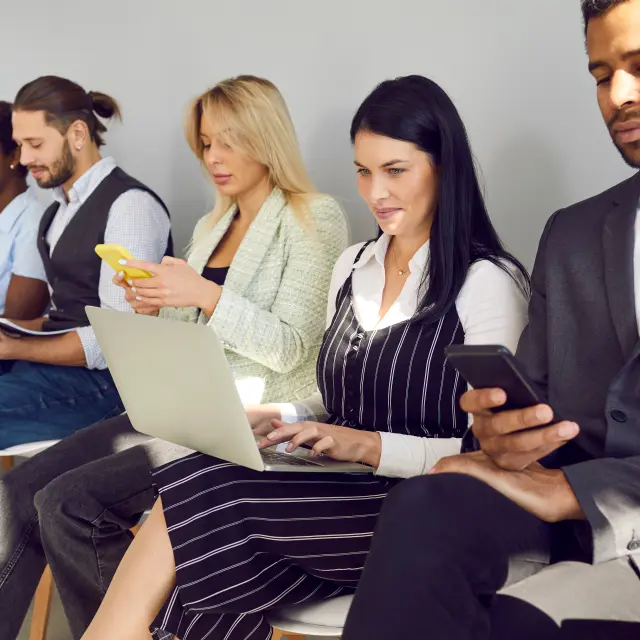 Different diverse multiethnic mixed race business people in smart casual clothes holding laptops, using cellphones, reading papers, documents, CVs and resumes while waiting in line for job interview