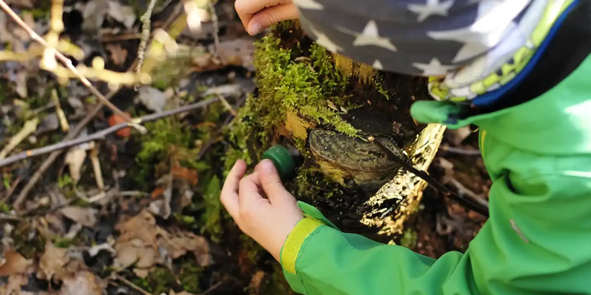 Enfant découvrant une cache de geocaching en famille en Chartreuse