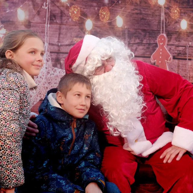 Enfants posant avec le Père Noël sur le marché de Noël de Châtelaillon-Plage, ambiance festive et familiale en Charente-Maritime.
