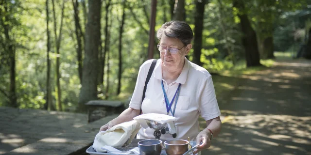 Une bénévole du services des lieux de cultes, prépare la messe à la Cathédrale de Verdure