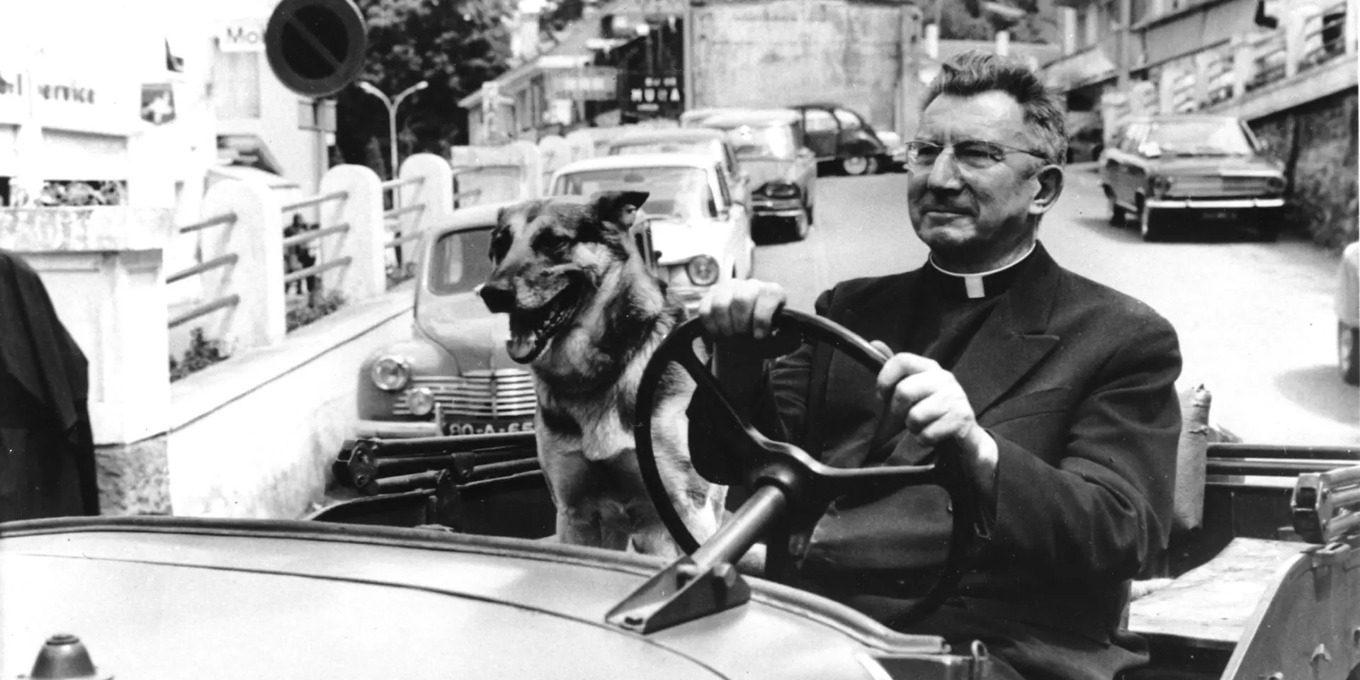 Mgr. Rodhain met zijn hond in een auto in Lourdes